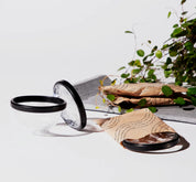 Three menstrual discs shown, one partially packaged and two unwrapped on a white surface with paper wrappers nearby.